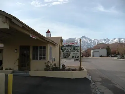 a parking sign in front of a building with a warning sign at Lone Pine Budget Inn in Lone Pine
