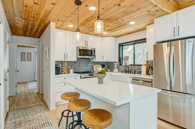 a kitchen with white cabinets and a counter with stools at Bolzano's Getaway in Truckee