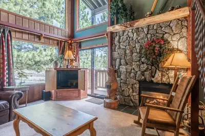 a living room with a fireplace and a stone wall at New Listing 2 bedroom and Loft 2 bath Summit E Bldg 12 condo sleeps 8 Steps to Eagle Lodge Chair 15 in Mammoth Lakes