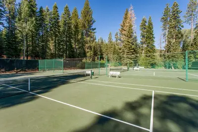 two tennis courts with trees in the background at Aspen Grove Condo in Truckee