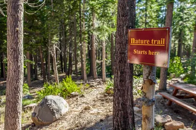a sign for a nature trail with a bench in the woods at Aspen Grove Condo in Truckee