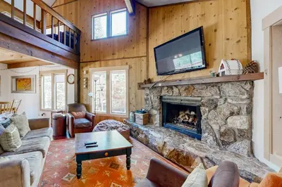 a living room with a stone fireplace and a tv at Wolfgang Dreams in Truckee