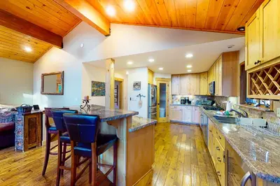 a large kitchen with wooden cabinets and blue bar stools at St Bernard Oasis in Truckee