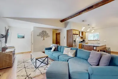 a living room with a blue couch and a kitchen at Homewood Cabin Among the Pines in Homewood