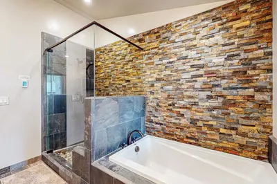 a bathroom with a tub and a brick wall at Prospector Palace in South Lake Tahoe