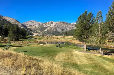 a golf course with a pond and mountains in the background at Resort at Squaw Creek's 605 in Olympic Valley
