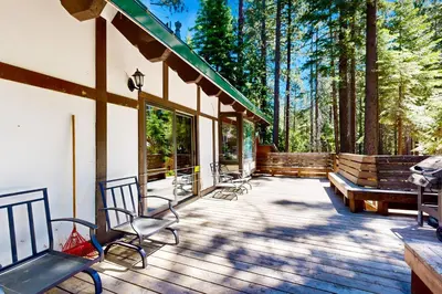 a deck with chairs and benches in the woods at Alpine Haven in Tahoe City