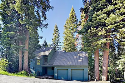 a house with a garage in the middle of a forest at Pathway Paradise in Truckee