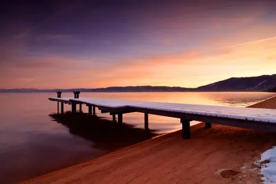a dock on a lake with a sunset in the background at Hank Monk Manor in South Lake Tahoe