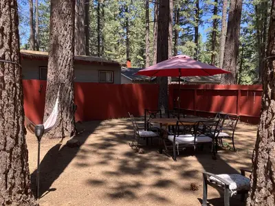 a table and chairs with an umbrella in the woods at Genoa Haven in South Lake Tahoe