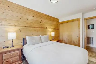 a bedroom with a white bed and a wooden wall at Alpine Retreat in Truckee