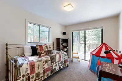 a bedroom with a bed and a table and windows at Schussing Paradise in Truckee