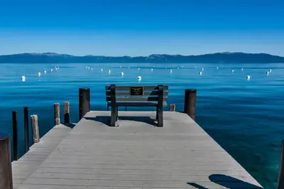 a bench sitting on a pier next to the water at West Shore Retreat in Tahoma