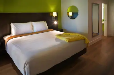 a bedroom with a large bed with a yellow blanket on it at Foothills Motel in Auburn