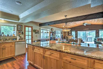a large kitchen with wooden cabinets and a large island at Gorgeous Oakhurst Retreat with Swimming Hole! in Oakhurst