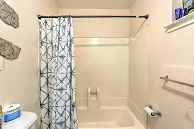 a bathroom with a shower curtain and a toilet at Gorgeous Oakhurst Retreat with Swimming Hole! in Oakhurst