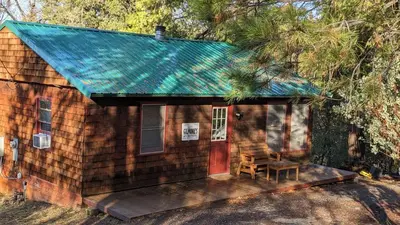 a small wooden house with a red door and a bench at Gilmore Cabin in Miramonte