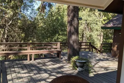 a wooden deck with a bench and a tree at Pierce's Cabin in Miramonte