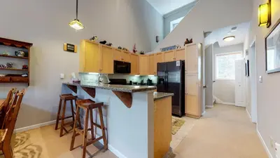 a kitchen with a black refrigerator and wooden cabinets at Mammoth Green #205 condo in Mammoth Lakes