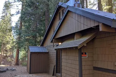 a building with a garage next to a forest at King's Cabin in Wilsonia