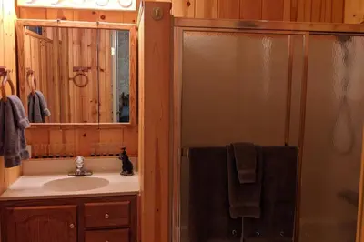 a bathroom with a sink and a shower with a mirror at King's Cabin in Wilsonia