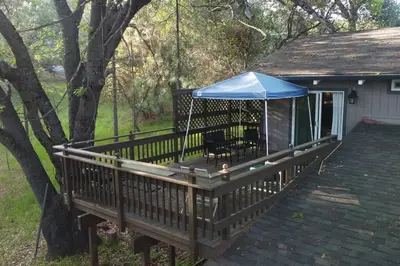 a porch with a blue umbrella on top of it at Mountain Cabin near Yosemite in Groveland
