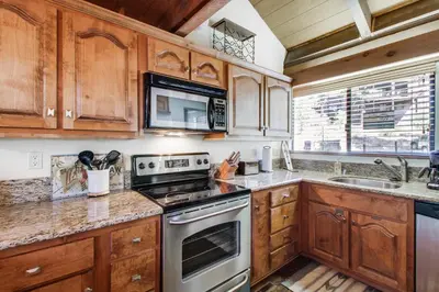 a kitchen with wooden cabinets and a stove top oven at Mill Camp Gem in Ponderosa Fairway Estates