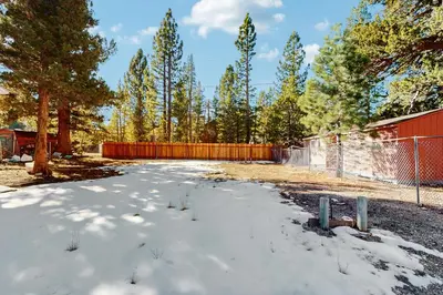 a yard covered in snow with a fence and trees at Apache Adventures in South Lake Tahoe