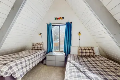 two beds in a attic room with blue curtains at Arrowhead Escape in South Lake Tahoe