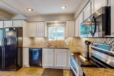 a kitchen with white cabinets and a black refrigerator at Cougar Haven in South Lake Tahoe