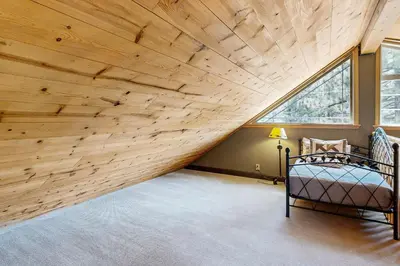 an attic bedroom with a wooden ceiling and a bed at Muhlebach Haven in Truckee