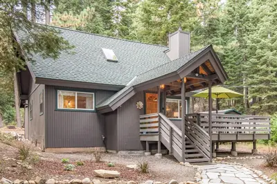 a small house with a porch and an umbrella at Cabin in the Woods in Tahoma