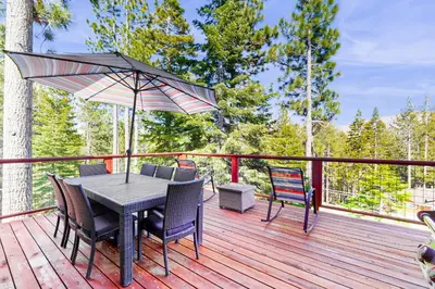 a table and chairs on a deck with an umbrella at Pooewin Place in South Lake Tahoe
