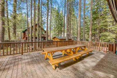 a wooden deck with a picnic table in the woods at Montgomery Estates Ski & Beach Haven in South Lake Tahoe