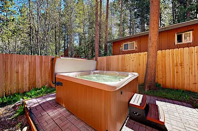 a hot tub sitting on a patio next to a fence at Cellador Charms in South Lake Tahoe