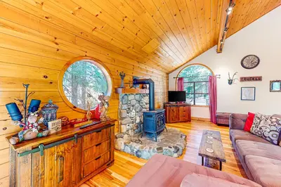 a living room with a stone fireplace in a log cabin at The Bear's Lair House in Truckee
