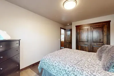 a bedroom with a bed and a dresser and wooden doors at Arrowhead Adventures in South Lake Tahoe