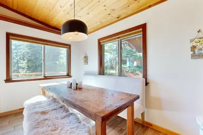 a dining room with a wooden table and windows at Spectacular Lakeview Cabin in Kings Beach