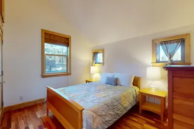 a bedroom with a bed and two windows at Cottage Charms in South Lake Tahoe