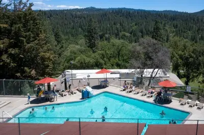 a large swimming pool with people sitting around it at New Luxury 5BR Cabin in Pine Mountain Lake! 1 Minute to Beach! Massage Chair! Close to Yosemite! Perfect for Retreats and Escapes All Seasons! in Groveland