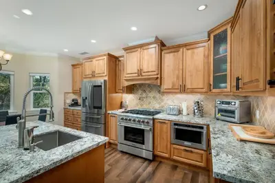a kitchen with wooden cabinets and stainless steel appliances at New Luxury 5BR Cabin in Pine Mountain Lake! 1 Minute to Beach! Massage Chair! Close to Yosemite! Perfect for Retreats and Escapes All Seasons! in Groveland