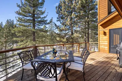 a table and chairs on a deck with trees at Creekside at Northstar home in Truckee
