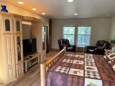 a bedroom with a bed and chairs and a television at Cozy Cabin in Arnold ! in Arnold