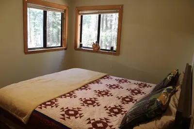 a bed in a bedroom with two windows at Fully updated Truckee cabin with plenty of beds in Truckee