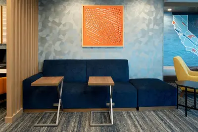 a blue couch in a room with two tables at Holiday Inn Express & Suites - Hollister by IHG in Hollister