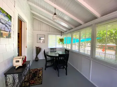 a dining room with a table and chairs and windows at Birdwatch Cottage With River Beach Pass in Three Rivers