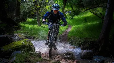a man riding a bike through a stream at Birdwatch Cottage With River Beach Pass in Three Rivers