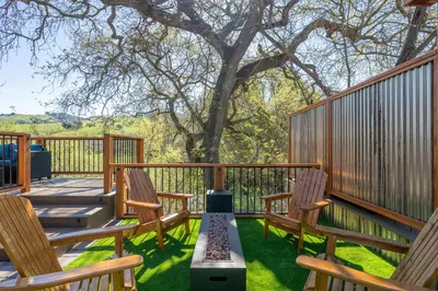 a deck with three wooden chairs and a tree at Casa de Fruta Cabins, Inn & RV Park in Hollister