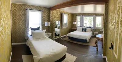 a bedroom with two beds and a room with two windows at The Bodie Hotel in Bridgeport