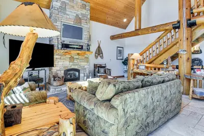 a living room with a couch and a stone fireplace at 2 Cabins Group and Family Getaway in Arnold! in Arnold